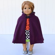 a doll wearing a purple cape and shoes