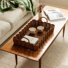 a wicker tray on a coffee table with two cups and saucers in it