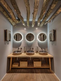 a bathroom with two sinks, mirrors and wooden beams in the ceiling is lit by lights