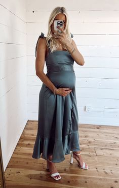 a pregnant woman taking a selfie in front of a mirror wearing a grey dress