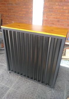 a black and yellow bar sitting next to a brick wall in a room with grey flooring