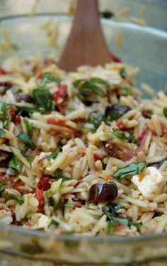 a bowl filled with rice and olives next to a wooden spoon