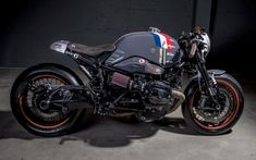 a black motorcycle parked in a garage next to a cement wall with an american flag painted on it