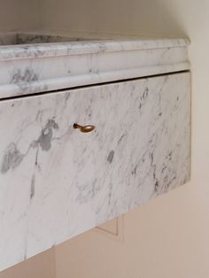 a white marble cabinet with brass handles