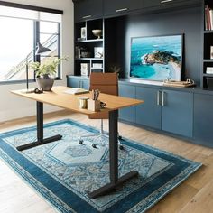 a living room with a desk and bookcases on the wall next to a large window