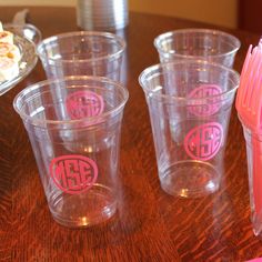 plastic cups with monogrammed initials are lined up on a table next to a pink straw