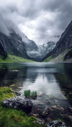 a lake surrounded by mountains under a cloudy sky