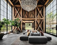 a living room with large windows, couches and a chandelier hanging from the ceiling