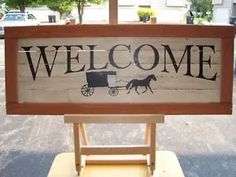 a wooden sign that says welcome with a horse drawn carriage on it's back