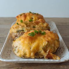 two cheesy pastries on a white plate sitting on a wooden table top