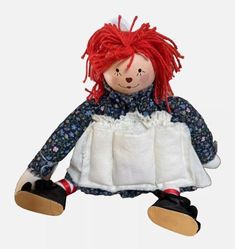 a doll with red hair sitting on the ground