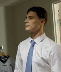 a man in a white shirt and blue tie standing next to a mannequin