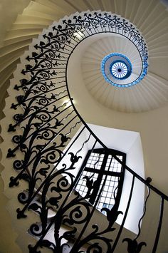 a spiral staircase with wrought iron railing and blue glass window