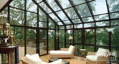 a living room filled with furniture and lots of glass walls on top of a wooden floor