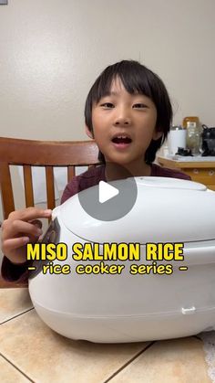 a young boy sitting at a table with a rice cooker in front of him