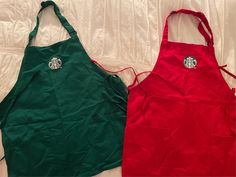 two aprons with starbucks logos on them are laying next to each other, one is red and the other green