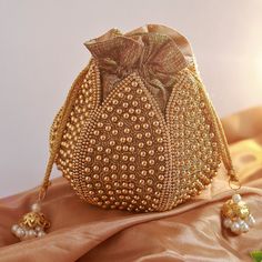 Discover the Elegant Lotus Potli Bag by THE TAN CLAN Elevate Your Style with Our Unique Embroidered Indian Bridal Potli Bag by THE TAN CLAN Transform your accessory collection with the Elegant Lotus Potli Bag--a stunning fusion of traditional craftsmanship and modern design. This exquisite embroidered potli bag is perfect for weddings, engagements, bridesmaid gifts and anniversary gifts. With its intricate detailing and luxurious finish, this bag is a must-have for anyone looking to add a touch Gold Potli Bag With Dori Work For Reception, Gold Potli Bag For Diwali Reception, Festive Gold Potli Bag For Reception, Bollywood Style Gold Bag For Reception, Gold Bridal Accessories For Festive Occasion, Embellished Potli Bag For Festivals And Celebrations, Traditional Gold Potli Bag For Reception, Traditional Bags With Gold Embroidery For Reception, Gold Embroidered Bag For Reception