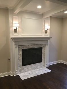 an empty living room with a fireplace and hard wood floors