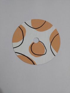 an orange and white circular object with black lines on the bottom, sitting on a gray surface