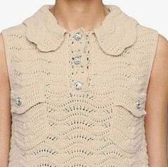 a woman wearing a crocheted sweater with buttons on the collar and sleeves,