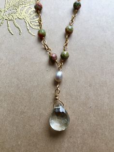 "A handmade chain of 12 faceted Unakite beads leads to a sparkling, faceted Green Amethyst drop hanging by a small Fresh Water Pearl. The closure features an additional Unakite bead. - 18\" long - gold-fill chain - Unakite, Pearl, and Green Amethyst - strong gold-fill clasp Arrives in a beautifully wrapped box with a gold-embossed bee design on the cover, a ribbon, and matching tissue paper." Briolette Crystal Necklace With Gemstone Beads For Healing, Briolette Gemstone Beads Crystal Necklace For Healing, Healing Briolette Gemstone Beads Crystal Necklace, Healing Teardrop Pendant Necklace With Gemstone Beads, Teardrop Gemstone Necklaces For Healing, Bohemian Briolette Crystal Necklaces For Jewelry Making, Briolette Gemstone Bead Necklace As A Gift, Briolette Gemstone Beads Necklace As Gift, Artisan Jewelry With Faceted Beads As A Gift