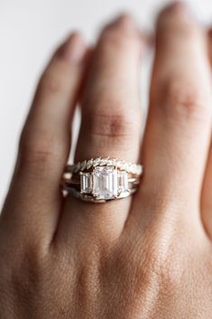 a woman's hand with a ring on it that has an emerald stone in the middle