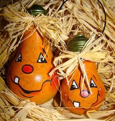 two oranges with faces painted on them sitting in hay