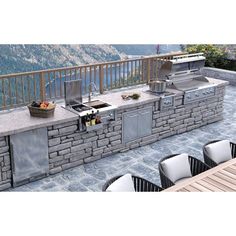 an outdoor kitchen with grills and chairs on the side of it, overlooking a mountain range