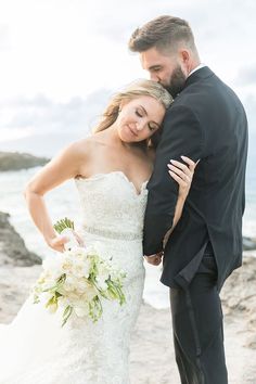 a bride and groom embracing on the beach