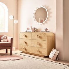 a baby's room with a dresser, mirror and teddy bear on the floor