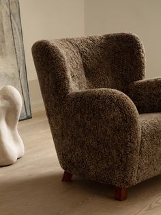 a brown chair sitting on top of a hard wood floor next to a white sculpture