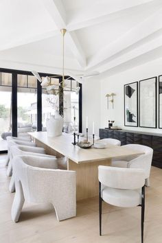 an elegant dining room with white chairs and wooden table