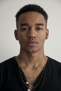 a young man with piercings on his nose looking at the camera while wearing a black shirt