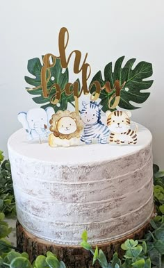 there is a cake that has animals on it and leaves around the top, along with an elly party sign