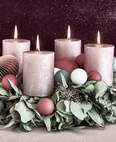 some candles are sitting next to some green leaves and other decorations on a table with purple speckles