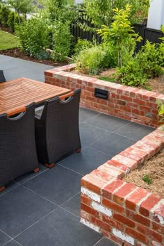 an outdoor dining table and chairs on a patio with brick walls in the back ground