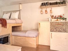 a bedroom with bunk beds, drawers and shelves on the wall next to a fireplace