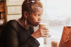 a woman sitting at a table drinking coffee