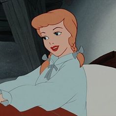 a woman sitting on top of a bed in a blue dress and white collared shirt