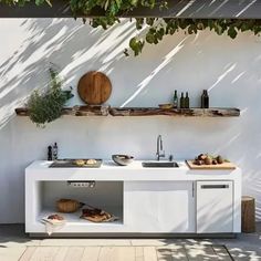 an outdoor kitchen with sink, counter and shelves on the outside wall next to it