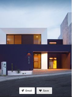 a modern house with dark blue walls and wooden shutters on the front door is lit up at night