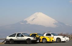 two cars parked next to each other in front of a mountain