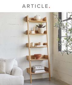 a living room with a white couch and wooden shelves on the wall next to a window