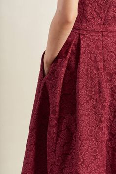 the back of a woman's red dress, with her hands on her hips