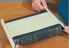 a person cutting paper with a pair of scissors on top of a book that is open