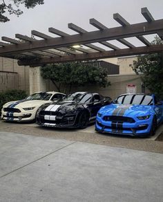 three cars parked in front of a building under a pergolated roof with wooden slats