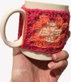 a hand holding a coffee cup with a crochet design on the outside and inside