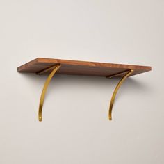 a wooden shelf with two brass brackets on it