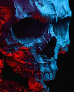 a skull with red and blue paint on it's face is shown in the dark