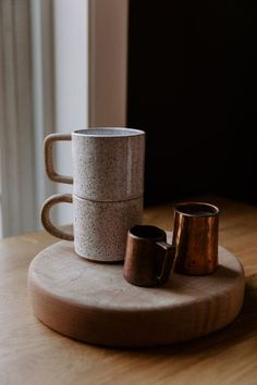 two coffee cups sitting on top of a wooden tray